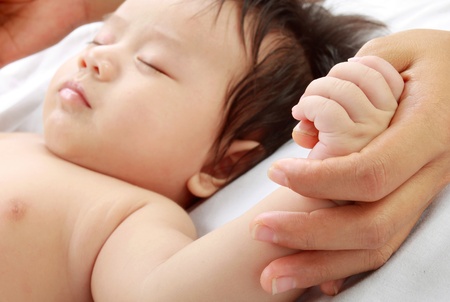 Cute baby holding mom's handの写真素材