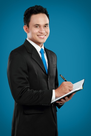 Portrait of a handsome young business man with pen writing on binder clipの写真素材