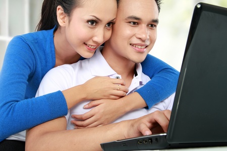 Portrait of smiling young couple using a laptopの写真素材