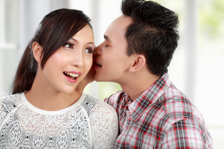 young man whispering something to his girlfriend