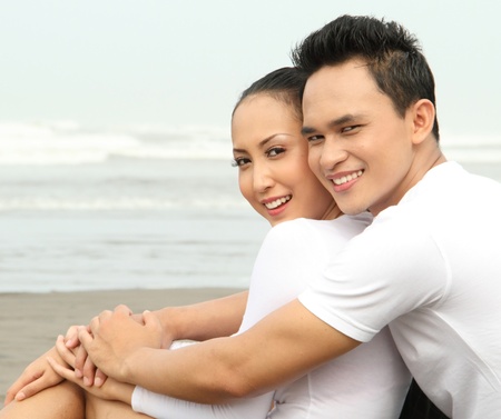 Close up Portrait of a happy young man hugging his girlfriend at the beachの写真素材