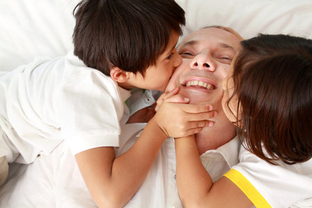 son kissing their father against a white background