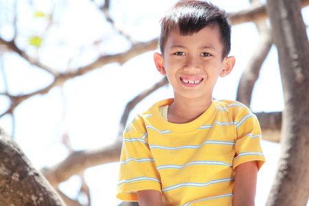Portrait of happy Children sitting on a branch of a tree