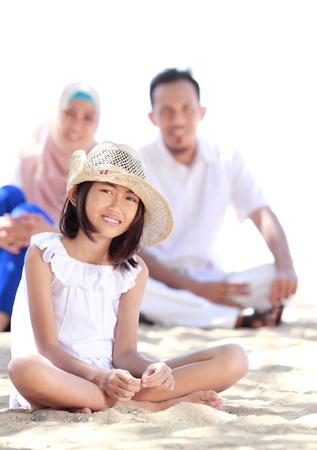 Portrait of young little girl in the beach smiling with her parent as backgroundの写真素材
