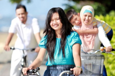 Happy asian family riding bikes in the beautiful morning at the beachの写真素材