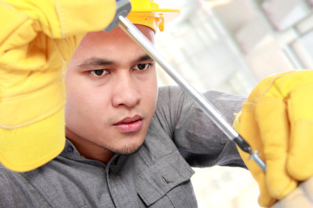 closed up young worker installing screws with screwdriver