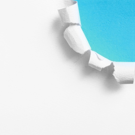 Piece of white paper with torn edge over blue backgroundの写真素材