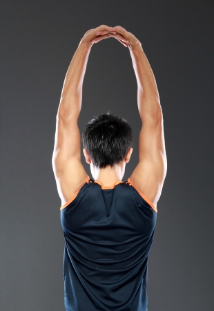 young fitness man making stretching exercises seen from behindの写真素材