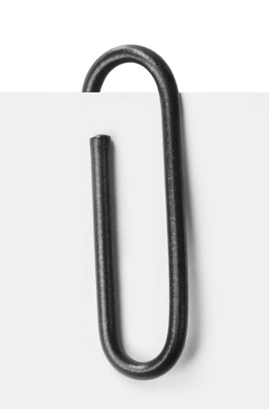 Close up of a black paper clip attached to sheet of paperの写真素材