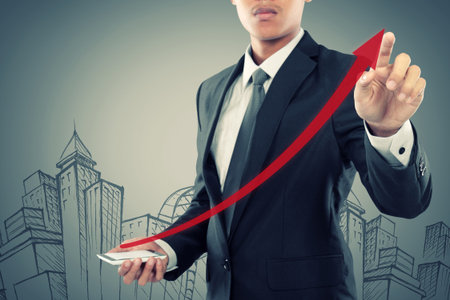 Businessman drag a rising arrow at smartphone, representing business growth, on virtual background.の写真素材