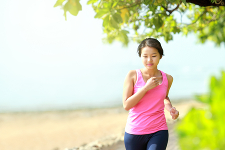Beautiful fitness model in pink running on the beachの写真素材