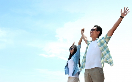 Portrait of asian young couple standing and raised their hands to the skyの写真素材