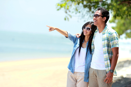 Portrait of romantic couple walking by the beachの写真素材