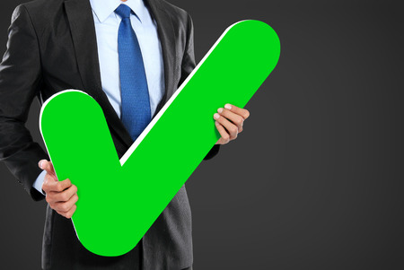 portrait of businessman holding green check mark iconの写真素材
