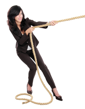Business competition. Young business woman pulling a rope isolated on white backgroundの写真素材