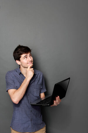 portrait of handsome young man with laptop pc looking up to copy spaceの写真素材