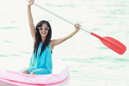 woman having fun kayaking on a sunny day at the beachの写真素材