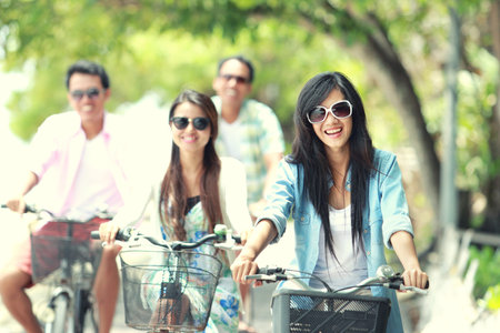 carefree group friends having fun and smiling riding bicycle during the summer day