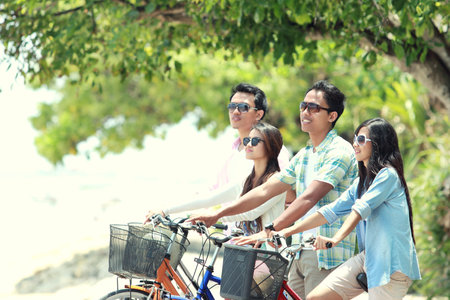carefree group friends having fun and smiling riding bicycle during the summer day
