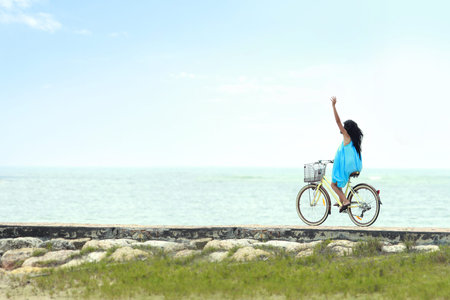 carefree woman having fun and smiling riding bicycle at the beachの写真素材