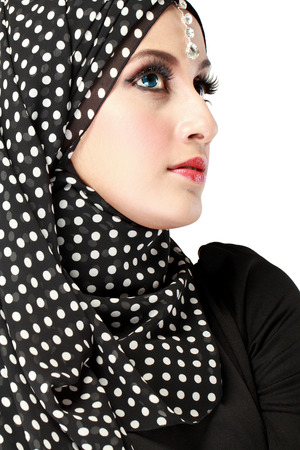 Fashion portrait of young beautiful muslim woman with black scarf isolated on white backgroundの写真素材