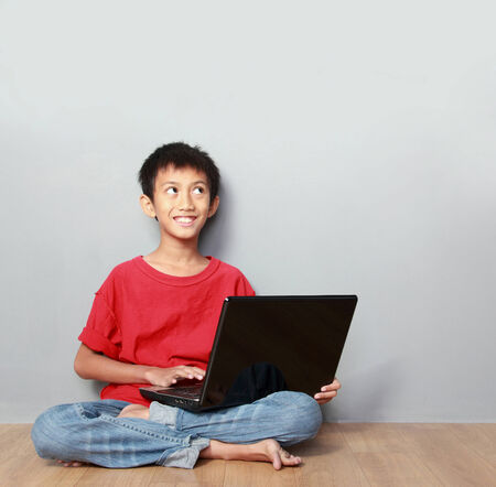 portrait of asian kid using laptop on grey backgroundの写真素材