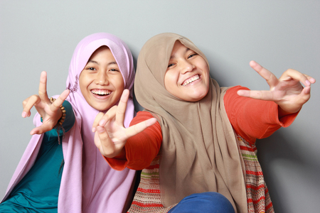 portrait of attractive two young muslim kid having fun together on grey backgroundの写真素材