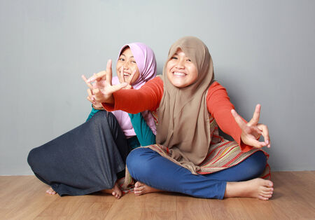 portrait of attractive two young muslim kid having fun together on grey backgroundの写真素材
