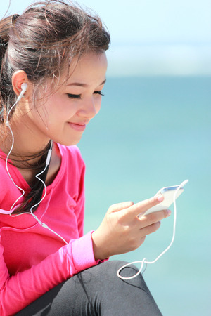 Portrait of sporty young woman in sports wear using cellphoneの写真素材