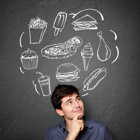 portrait of Happy young man looking up thinking what to eat. fast food conceptの写真素材