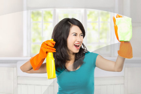portrait of Attractive young woman cleaning windows isolated over white background