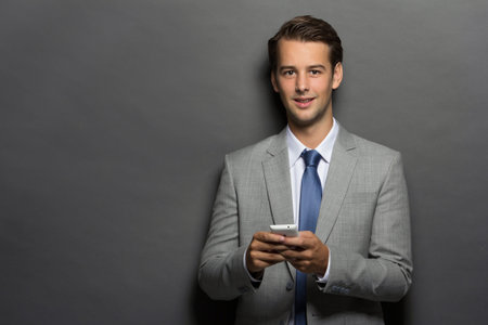 Young business man texting a message with phone over gray backgroundの写真素材