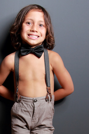 portrait of cute little boy smiling and posing on dark grey backgroundの写真素材