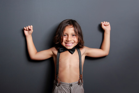 portrait of cheerful cute little boy posing and smiling on dark grey backgroundの写真素材