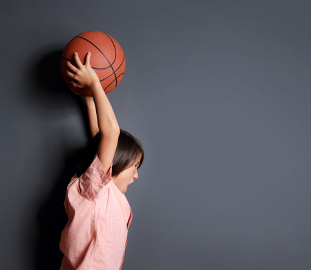 portrait of cute little boy holding a basketball and will throw itの写真素材