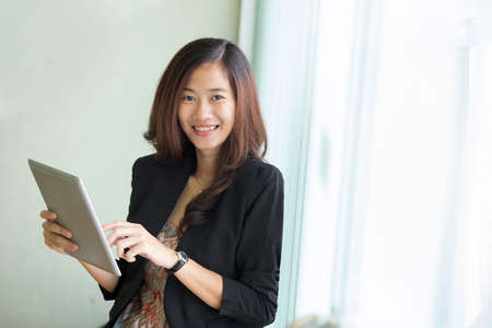 A portrait of a Young businesswoman standing while look at a tablet pcの写真素材