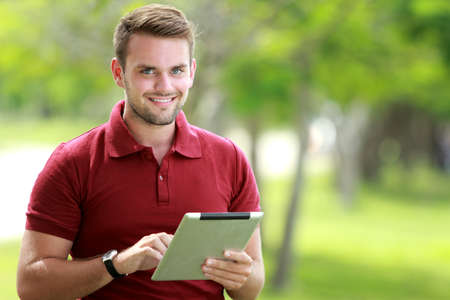 portrait of college student looking at camera while holding a tablet with copy spaceの写真素材