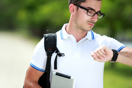close up portrait of a handsome college student saw the time on his watchの写真素材