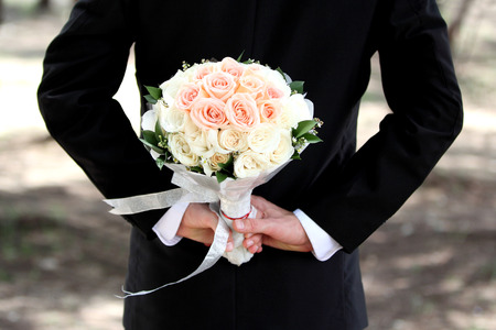 groom holding a bouquet behind his backの写真素材