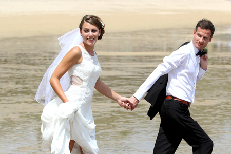 portrait of bride and groom hand to hand walking at the beachの写真素材