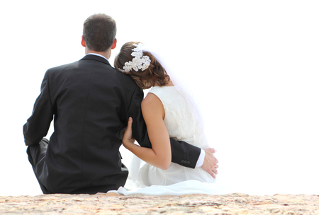 back view of romantic newlywed couple sitting on seashore with copy spaceの写真素材