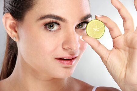 portrait of beautiful face of young model looking at camera with juicy lime in her handの写真素材