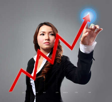 portrait of businesswoman up the chart with her fingers at grey backgroundの写真素材
