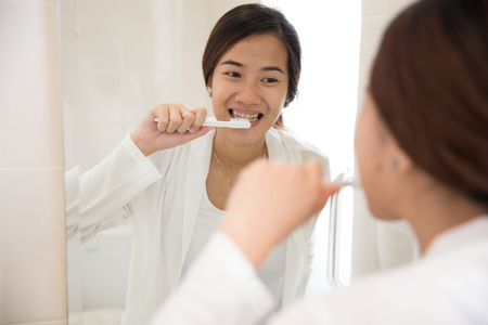 A portrait of a Beautiful asian woman brushing her teeth happilyの写真素材