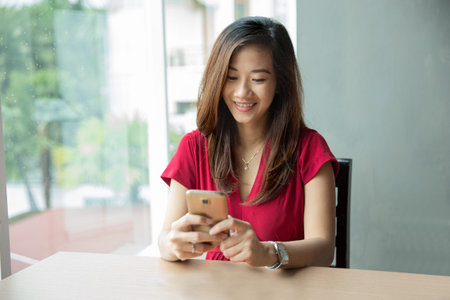 A portrait of an Asian woman holding a smartphone while having some fruit