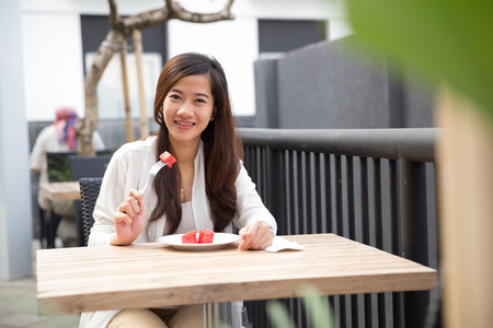 A portraiy of an Asian woman eating fruit happily, watermelonの写真素材
