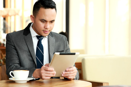 portrait of businessman reading an article on his tablets during coffee break with copyspaceの写真素材
