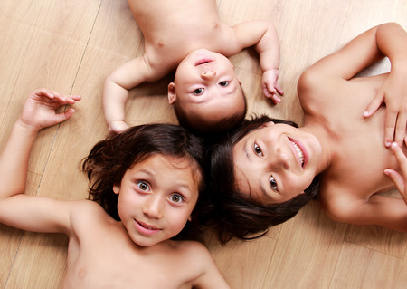 portrait of three little brothers smiling while lying on the floorの写真素材