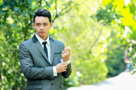 portrait of handsome groom fixing his sleeves with copy spaceの写真素材