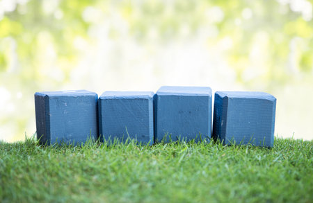 close up still life portrait of wooden blocks on a green grass, ready for your text with bokeh backgroundの写真素材